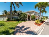 Stunning two-story home boasts a paver driveway, lush landscaping, and a charming covered entrance at 3 Paradise Ln, Treasure Island, FL 33706