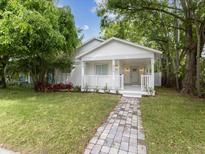 Charming home with a brick walkway, front porch, manicured lawn, and mature trees at 445 33Rd N Ave, St Petersburg, FL 33704