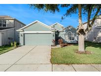 Charming single-story home featuring a well-manicured lawn and an attached two-car garage at 9954 N Jasmine Brook E Cir, Land O Lakes, FL 34638