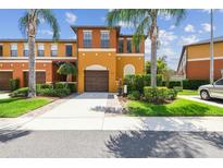 Charming multi-story townhome featuring a private garage, manicured lawn and vibrant landscaping with tropical palm trees at 30130 Mossbank Dr, Wesley Chapel, FL 33543