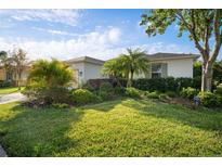 Charming single-story home with mature landscaping, lush green grass, and a well-maintained lawn at 5460 Sandy Shell Dr, Apollo Beach, FL 33572