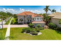 Elegant two-story home with a red tile roof, manicured lawn, lush landscaping, and a paver driveway at 6317 Marbella Blvd, Apollo Beach, FL 33572
