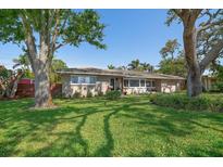 Charming single-story home with a lush green lawn and mature trees offering shade at 7909 Garden N Dr, St Petersburg, FL 33710