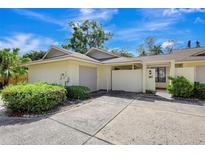 Inviting home exterior featuring a one car garage, quaint courtyard and well-maintained landscaping at 107 Parkside Colony Dr, Tarpon Springs, FL 34689
