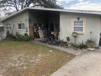 Modest single-story home featuring a front yard with a mix of concrete and grassy areas at 1911 E 143Rd Ave, Tampa, FL 33613