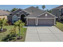 Charming single-story home with a well-manicured lawn and a spacious three-car garage at 2310 Wood Pointe Dr, Holiday, FL 34691