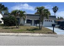 Charming single-story home with light exterior paint, beautiful palm trees, and an attached garage at 3542 Delta Pl, Holiday, FL 34691