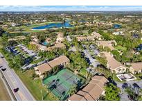 Scenic aerial view of the community featuring a golf course, lake, tennis courts, and lush landscaping at 4002 Crockers Lake Blvd # 1-128, Sarasota, FL 34238