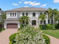 Stunning home with a lush, landscaped front yard, circular driveway, and beautiful palm trees at 5025 W Homer Ave, Tampa, FL 33629