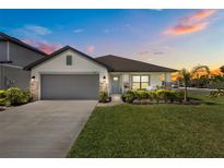Charming single-story home featuring a well-manicured lawn, gray garage door, and inviting front porch at sunset at 5938 164Th E Ave, Parrish, FL 34219