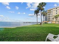 Beautiful waterfront property with lush green lawn, palm trees, and building featuring waterfront access and ample outdoor space at 6051 Sun Blvd # 111, St Petersburg, FL 33715