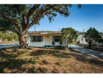 Charming single-story home with a large tree, a covered porch, and a well-maintained front yard at 7051 Dartmouth N Ave, St Petersburg, FL 33710