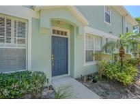 Charming home featuring a blue front door, light-green exterior, and lush, well-kept landscaping at 8341 Shallow Creek Ct, New Port Richey, FL 34653