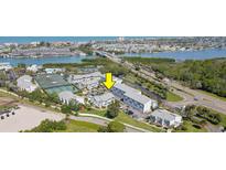 An aerial view of condo community, featuring tennis courts, waterway, and surrounding neighborhood at 14800 Walsingham Rd # 301, Largo, FL 33774