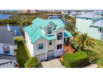 Stunning waterfront home with a vibrant teal roof and charming curb appeal in a desirable coastal community at 5623 Jobeth Dr, New Port Richey, FL 34652
