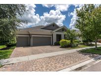 Well-maintained home featuring a three-car garage, brick driveway, and beautifully landscaped front yard at 6313 Brevada Ln, Apollo Beach, FL 33572