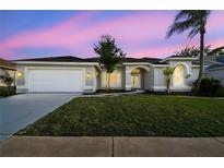Charming single-story home with a well-manicured lawn, attached garage, and inviting arched entryway at 8818 Poe Dr, Hudson, FL 34667