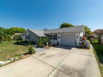 Charming single-story home with a well-manicured lawn, a two car garage, and a sunny sky at 12202 Meadowbrook Ln, Hudson, FL 34667