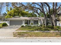 Charming single-story home with well-maintained landscaping and a two-car garage nestled under mature trees at 2029 Winding Oaks Dr, Palm Harbor, FL 34683