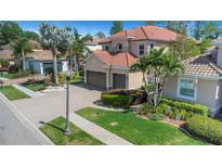 Charming two-story home with a well-manicured lawn, mature palm trees, and a beautiful brick driveway at 2630 Grand Lakeside Dr, Palm Harbor, FL 34684