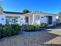 Charming single-story home featuring a white exterior, well-maintained landscaping, and stone accents on the entryway columns at 7114 Parrot Dr, Port Richey, FL 34668