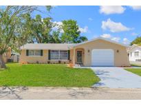 Charming single-story home with a well-maintained lawn, attached garage, and freshly painted driveway at 7336 Cherry Laurel Dr, Port Richey, FL 34668