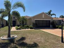 Charming single-story home featuring a well-manicured lawn, two-car garage, and lush tropical landscaping at 832 King Leon Way, Sun City Center, FL 33573