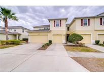 Inviting townhome featuring a light yellow facade, two-car garage, and well-maintained landscaping, creating an appealing curb appeal at 10822 Verawood Dr, Riverview, FL 33579