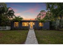 Charming single-story home with a well-manicured lawn, lush tropical landscaping, and a welcoming walkway to the front door at 1136 Serpentine S Dr, St Petersburg, FL 33705