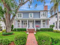 Charming two-story home featuring a welcoming front porch with swing, manicured lawn, and brick walkway at 1403 W Watrous Ave, Tampa, FL 33606