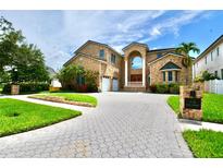 Stunning two-story brick home with an arched entry, a circular driveway, and lush landscaping at 441 Lucerne Ave, Tampa, FL 33606