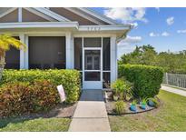 Charming home entrance featuring a screened porch and lush, landscaped surroundings at 5702 Tides Pl, Apollo Beach, FL 33572