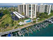 Expansive aerial view showcasing a waterfront condo community with a pool, boat docks, and covered parking at 690 Island Way # 707, Clearwater Beach, FL 33767