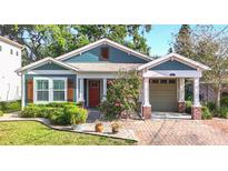 Charming home featuring a brick driveway, red door, and colorful landscaping, with inviting curb appeal at 917 W Alfred St, Tampa, FL 33603