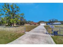 Sprawling single-story home with detached garage and a long driveway on a well-maintained lawn at 16247 Fringe Tree Dr, Spring Hill, FL 34610