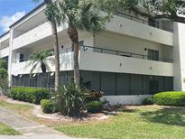 A three-story condo building with balconies, palm trees, and green landscaping with the windows looking out to a courtyard at 2583 Countryside Blvd # 3102, Clearwater, FL 33761