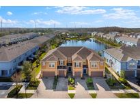 Beautiful exterior view of townhomes next to a lake with colorful facades and attached garages at 3214 Painted Blossom Ct, Lutz, FL 33558