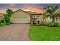 Inviting single-story home with a lush lawn, brick driveway, a two-car garage, and a terracotta-colored tiled roof at 5115 Tobermory Way, Bradenton, FL 34211