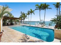 Beautiful backyard pool with spacious travertine deck, private dock, and lush tropical landscaping at 571 Johns Pass Ave, Madeira Beach, FL 33708