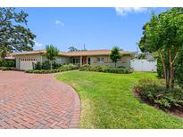 Charming one-story home featuring a brick driveway, well-manicured lawn, and lush landscaping at 8300 37Th N Ave, St Petersburg, FL 33710