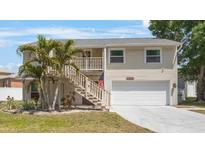 Charming two-story home featuring a two-car garage, front yard with palms, and staircase to the front door at 921 Lynnlea Ln, Tarpon Springs, FL 34689