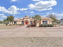 Elegant home with a red front door, well-manicured landscaping, and a circular driveway at 9460 Bearfoot Trl, Weeki Wachee, FL 34613