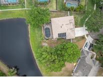 Aerial view of a home with a screened pool, long driveway, and adjacent to a scenic pond at 12304 Freesia Ct, Riverview, FL 33569