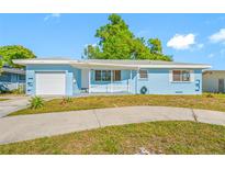 Charming light blue single-story home featuring an attached garage and a white picket fence at 1431 Kings Hwy, Clearwater, FL 33755
