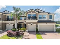 Beautiful townhome exterior with a two-car garage, lush landscaping, and a well-maintained brick driveway at 18860 Beautyberry Ct, Lutz, FL 33558