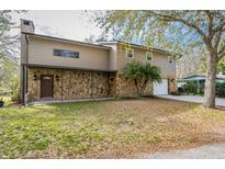 Two-story home featuring a stone facade, covered porch, mature landscaping, and a convenient attached two-car garage at 18914 5Th St, Lutz, FL 33548