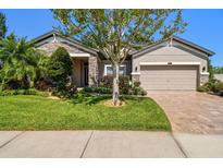 Charming home with well-manicured lawn, mature landscaping, and a brick paver driveway at 21627 Pearl Crescent Ct, Land O Lakes, FL 34637
