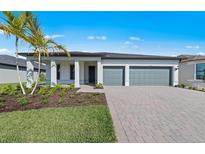 Beautiful single-story home with a two-car garage, brick driveway and a manicured lawn and tropical landscaping at 2731 Winding Creek Trl, North Port, FL 34289