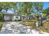 Charming single-story home featuring a spacious front yard with mature trees, a covered carport and a quaint picket fence at 3202 W Coachman Ave, Tampa, FL 33611