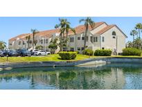 Well-maintained building exterior with lush landscaping, palm trees, pond and parking at 6131 Bahia Del Mar Blvd # 240, St Petersburg, FL 33715